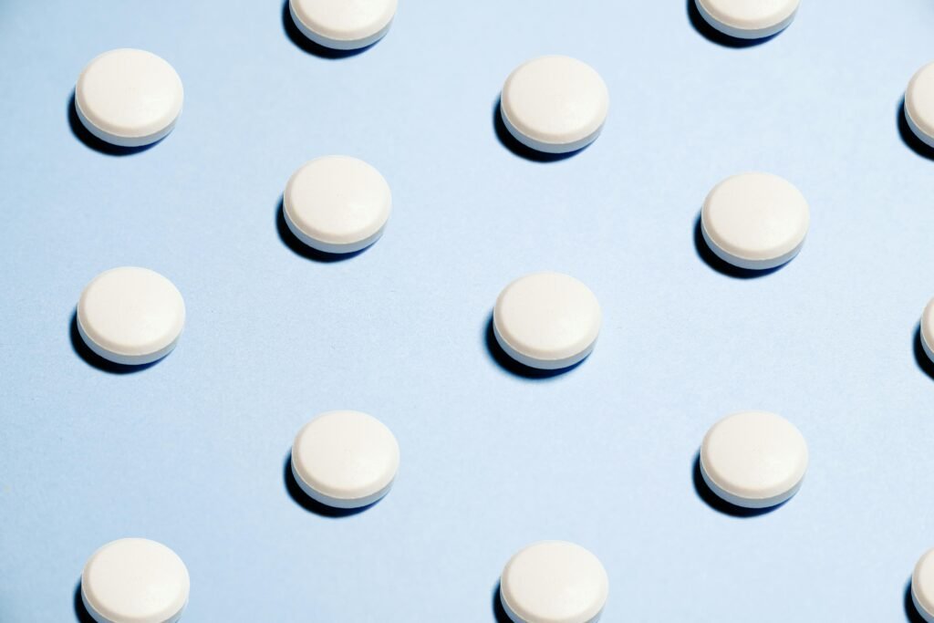 Array of white pills on a light blue background, ideal for healthcare themes.